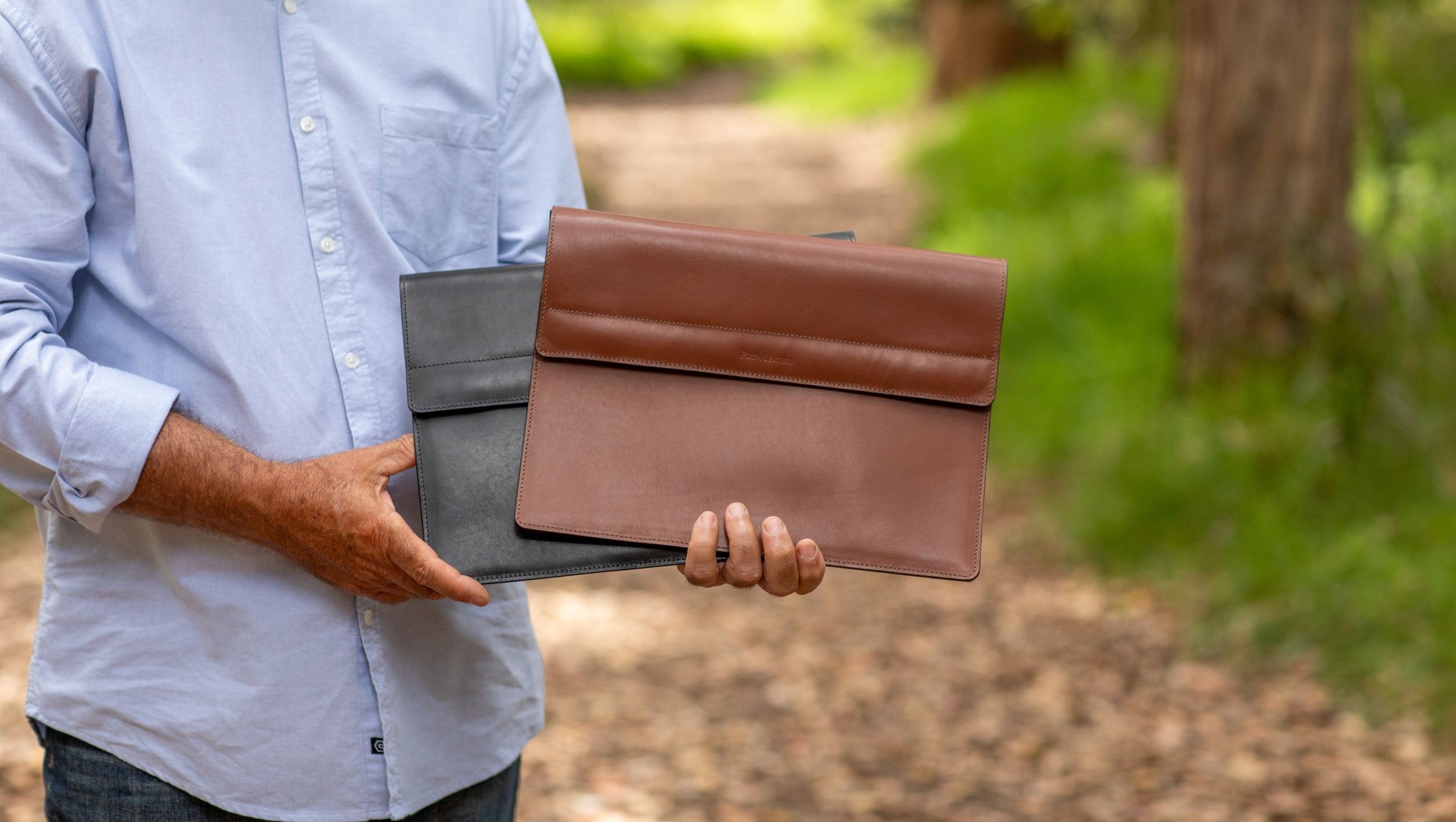 Man holding Porta bovine leather Laptop and Tablet Sleeve in black and brown  