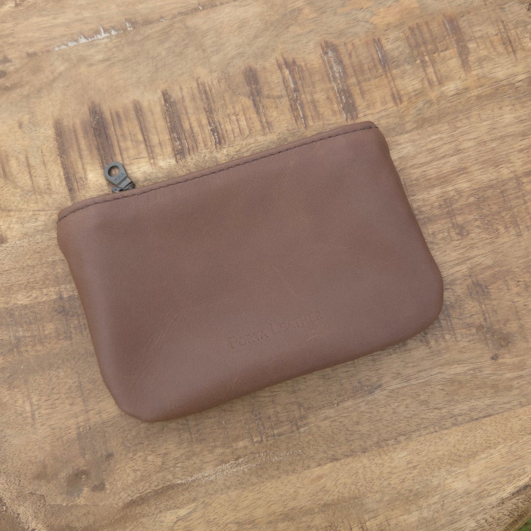 Brown Porta Leather mini pouch placed on a timber background.