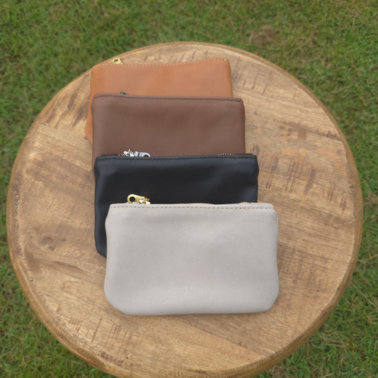 Collection of black, brown, grey and tan mini pouches displayed on a stool