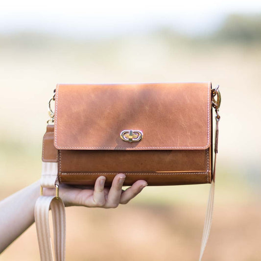 Tan Porta Leather handbag held by a person with a blurred natural background