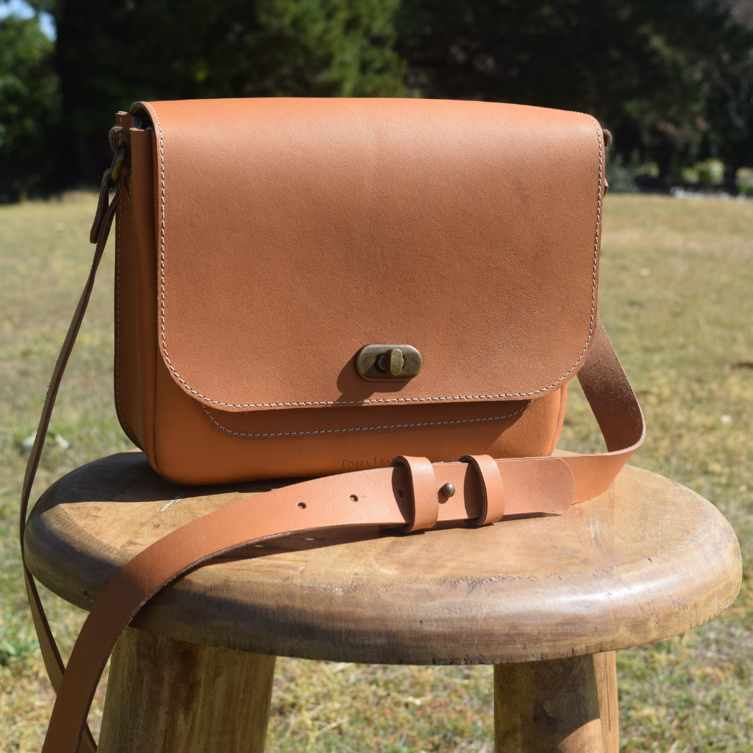 Porta Leather Dekota Saddle Bag in Heritage Tan with antique hardware sitting on chair