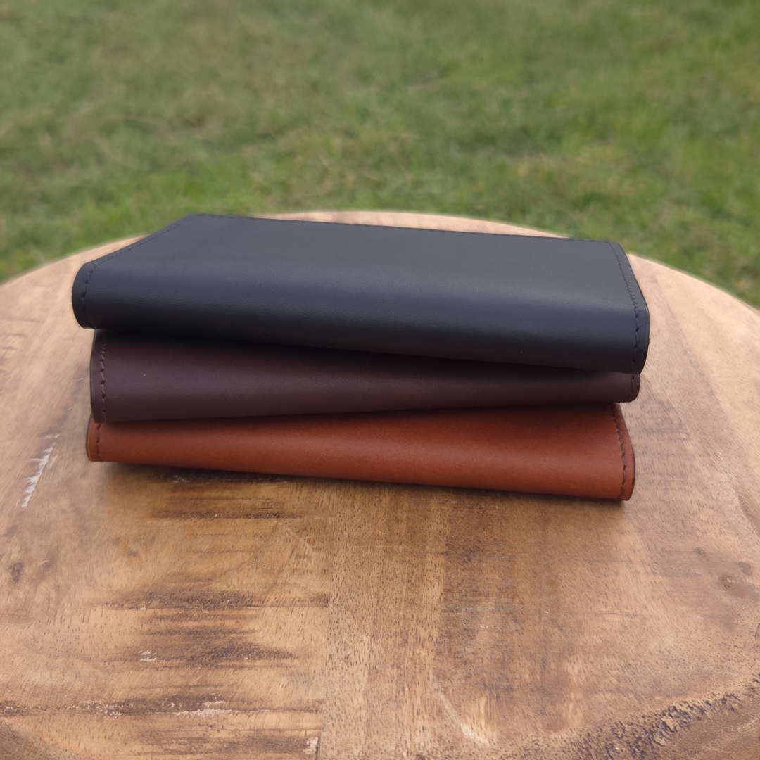 Porta Leather Passport Wallets stacked up on a stool in the colours of black, dark brown and brown.